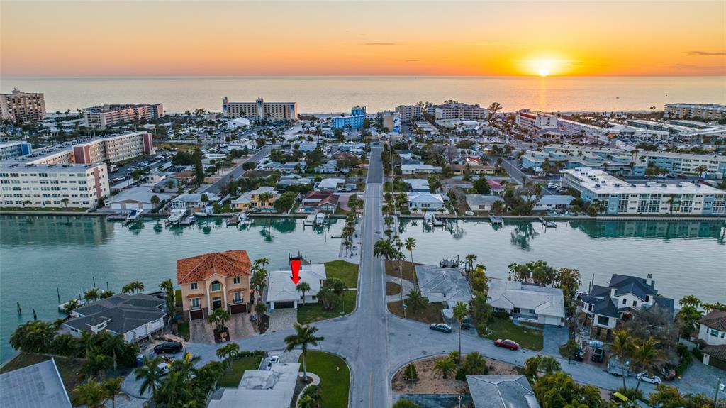 An aerial view shows a waterfront house with a red arrow pointing to its roof — 370 59TH AVENUE, ST PETE BEACH, FL