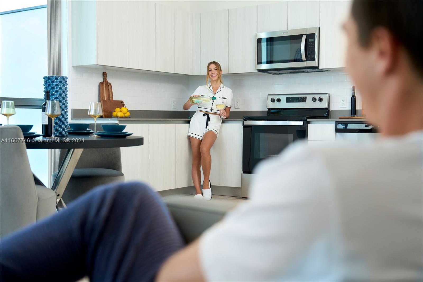A modern kitchen features white cabinetry, stainless steel appliances, and a dining table in foreground — 1809 Jackson St # 504, Hollywood FL 33020, HOLLYWOOD, FL