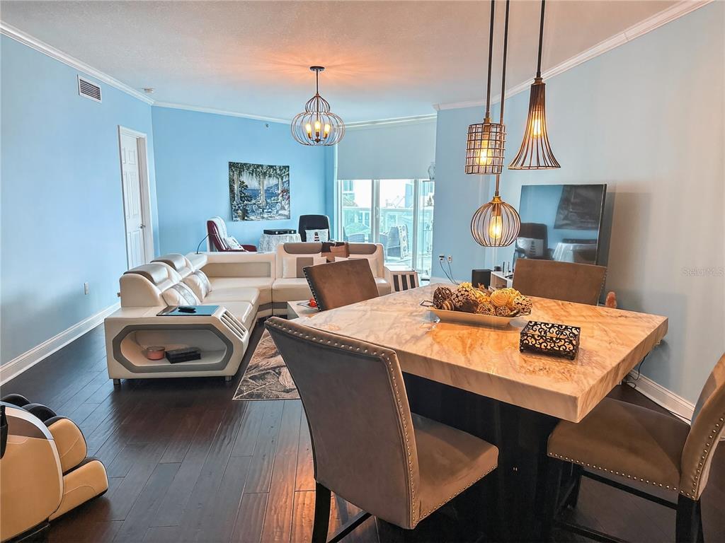 A dining area with a stone table and pendant lights opens into a living room — 231 RIVERSIDE DRIVE UNIT 208-1, HOLLY HILL, FL