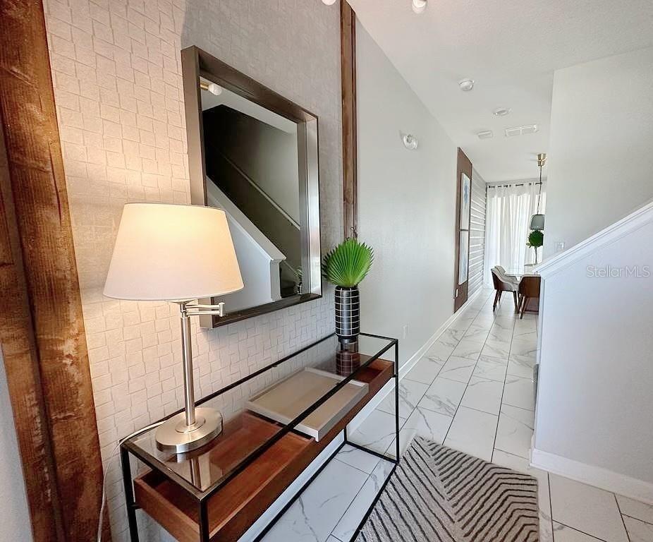 A hallway features a glass console table, a mirror, and a lamp against textured wallpaper — 468 OCEAN COURSE AVENUE, DAVENPORT, FL