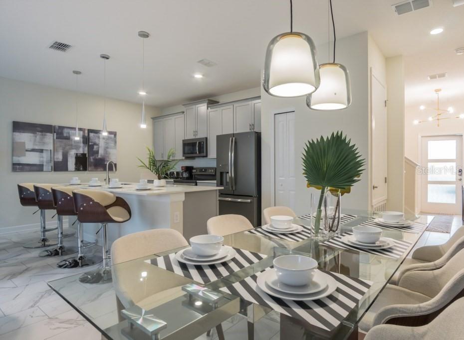 A modern kitchen and dining area featuring gray cabinetry, a glass table, and pendant lighting — 468 OCEAN COURSE AVENUE, DAVENPORT, FL