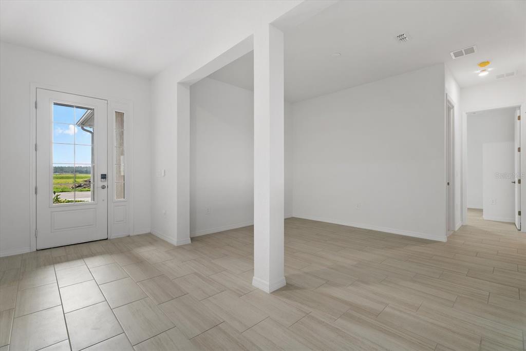 An entryway with light-colored tile flooring leads into an open room with white walls — 5918 MOUND KEY RUN, LAKEWOOD RANCH, FL