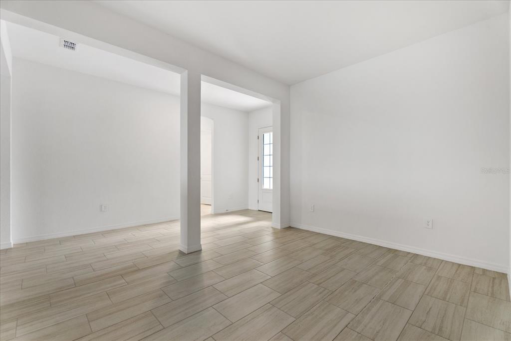 An empty room with white walls, light wood-look tile flooring, and a central support pillar — 5918 MOUND KEY RUN, LAKEWOOD RANCH, FL