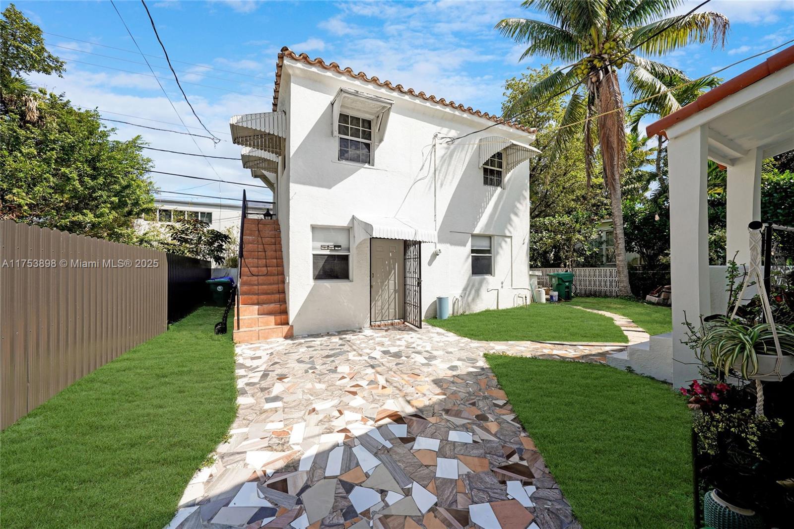 A two-story white stucco house features an exterior staircase and a mosaic tile patio — 4727 NE 1st Ct, Miami FL 33137, MIAMI, FL