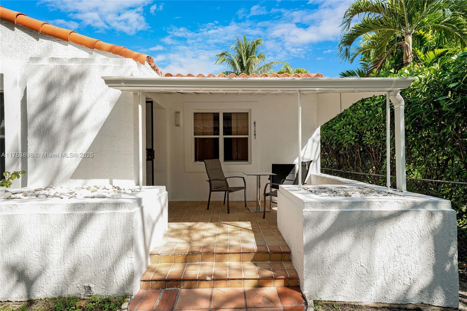 A white stucco house features a tiled patio with a small table and chairs — 4727 NE 1st Ct, Miami FL 33137, MIAMI, FL