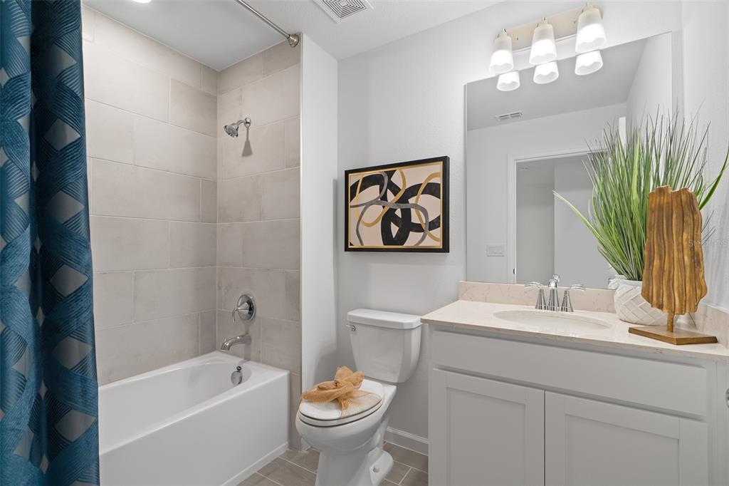A bathroom features a tub-shower combination, a white vanity, a toilet, and framed wall art — 3864 SE 36TH LANE, OCALA, FL