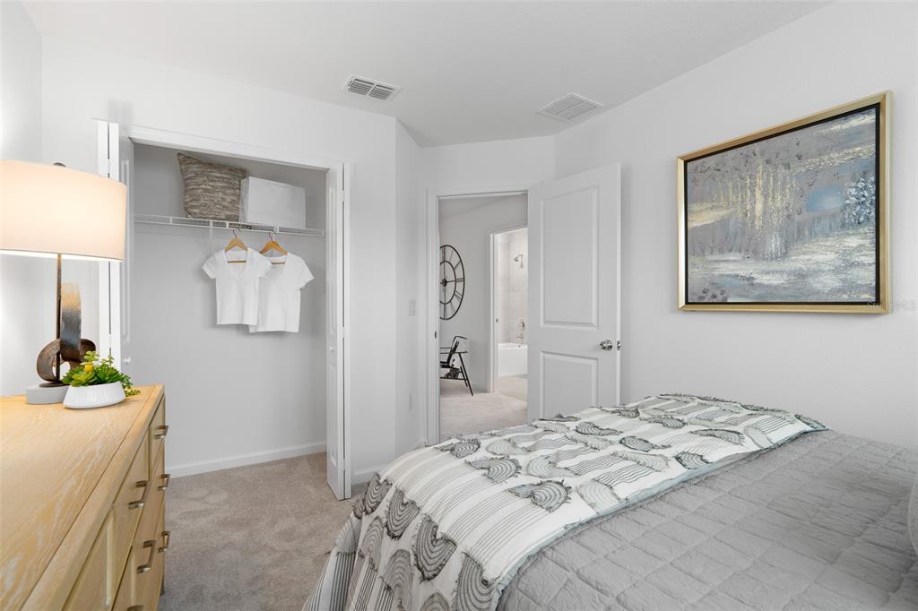 A bedroom features a bed, a dresser with a lamp, a closet, and an open doorway — 3864 SE 36TH LANE, OCALA, FL