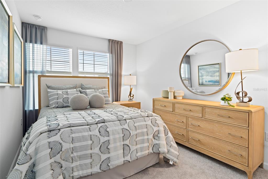 A bedroom features a bed with patterned bedding, a wooden dresser, and a round mirror — 3864 SE 36TH LANE, OCALA, FL