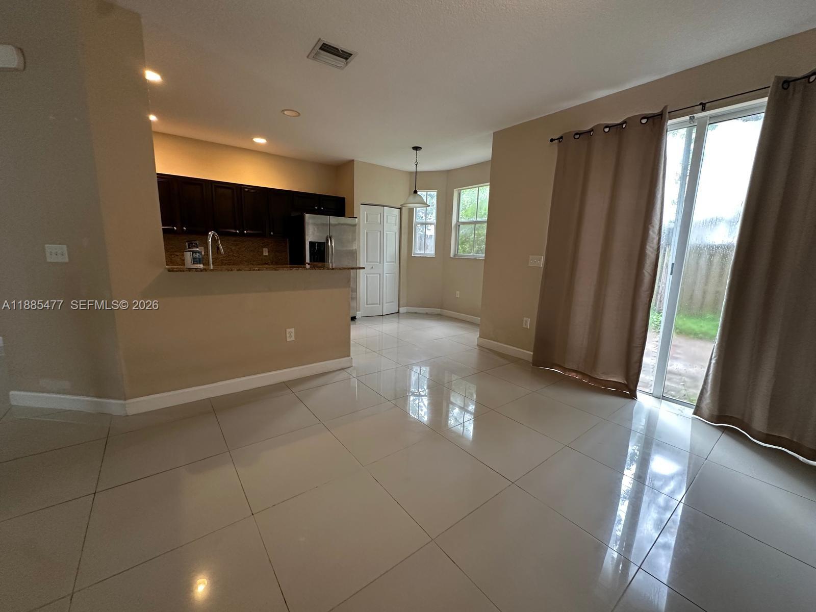 This kitchen and dining area features dark cabinets, granite countertops, and light tile flooring — 1026 NE 207th Ter # 1026, Miami FL 33179, MIAMI, FL