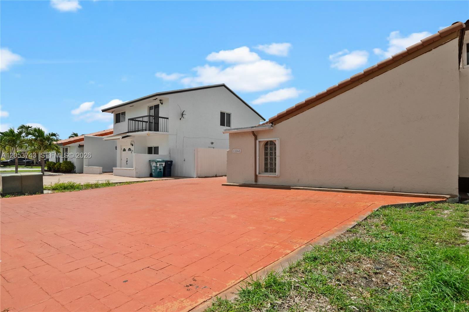 A paved driveway leads to a tan house with a tiled roof and a white building — 12262 SW 10th St, Miami FL 33184, MIAMI, FL
