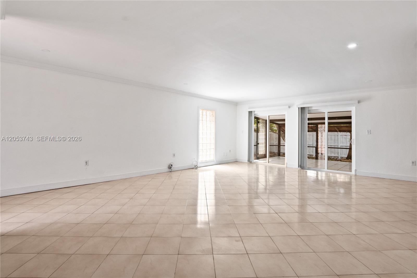 A spacious, empty room features white walls, light-colored tile flooring, and two sliding glass doors — 12262 SW 10th St, Miami FL 33184, MIAMI, FL
