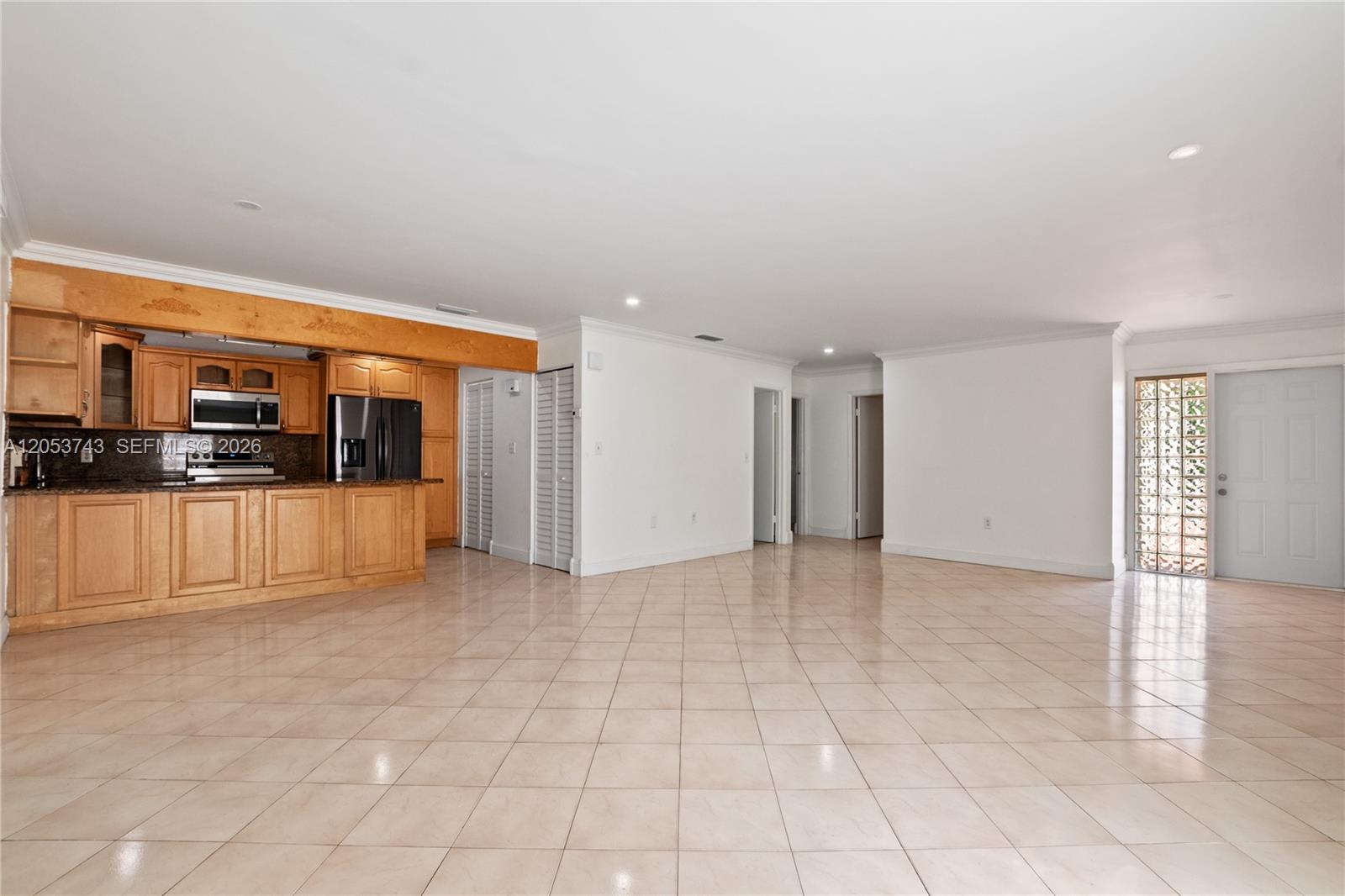 An open-concept kitchen with light wood cabinets overlooks a large, tiled living area — 12262 SW 10th St, Miami FL 33184, MIAMI, FL