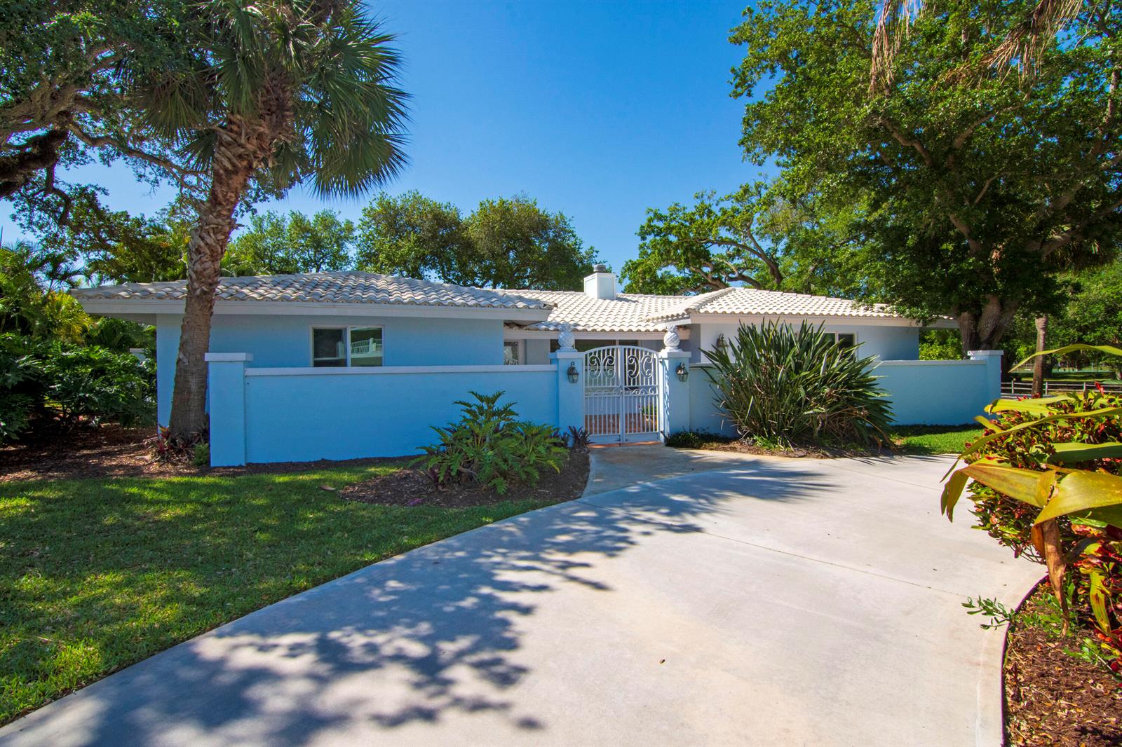 A light blue single-story house with a tiled roof and a gated courtyard entrance — 500 Gardenia Lane, Vero Beach FL 32963, VERO BEACH, FL