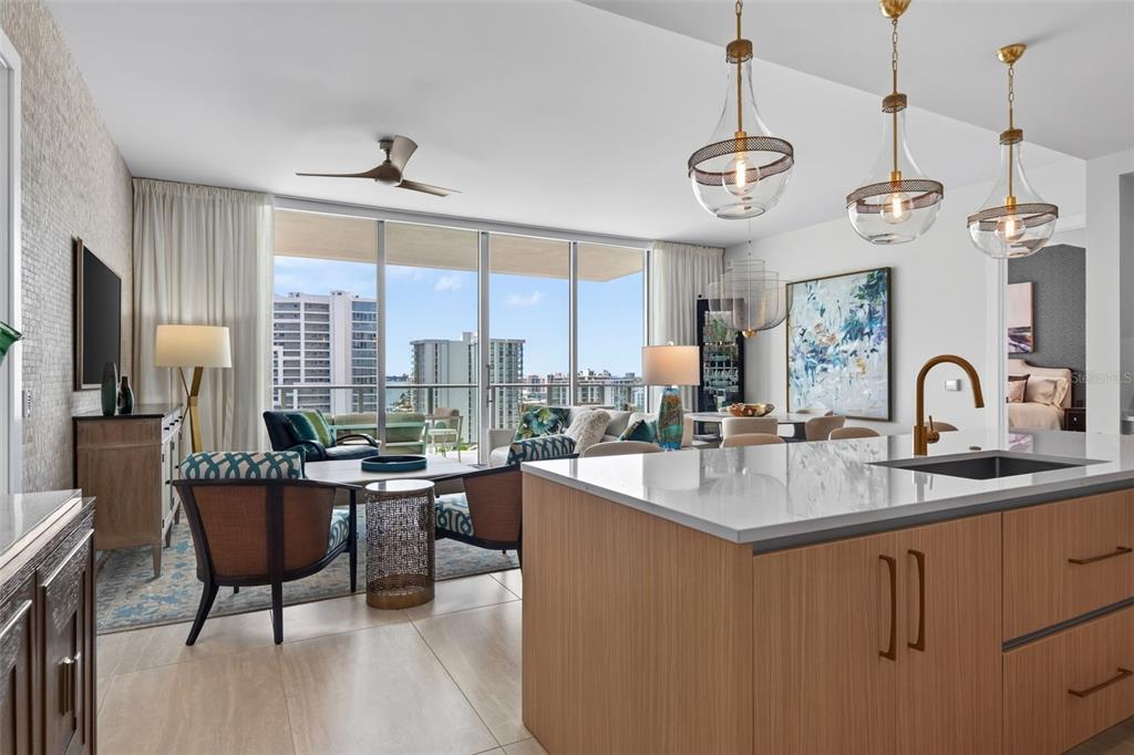 A modern open-concept living area features a kitchen island, dining space, and floor-to-ceiling balcony windows — 301 QUAY COMMONS UNIT 1009, SARASOTA, FL