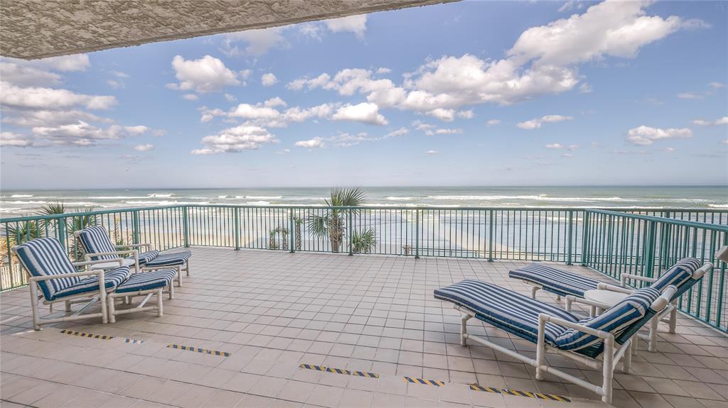 A tiled balcony overlooks the ocean with four striped lounge chairs and a metal railing — 3311 S ATLANTIC AVENUE UNIT 202, DAYTONA BEACH, FL