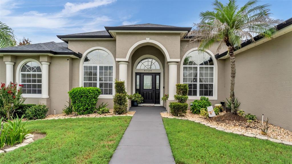 A single-story house with a beige stucco exterior, arched windows, and a central entryway — 6726 HARTSWORTH DRIVE, LAKELAND, FL