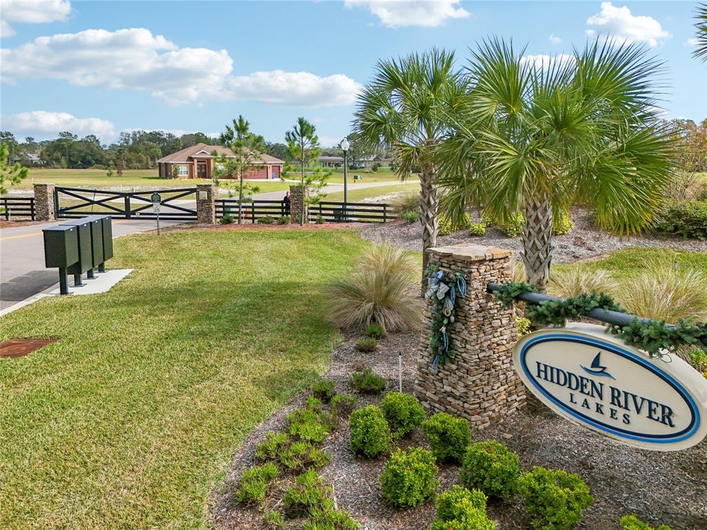 A stone monument sign for Hidden River Lakes stands near a gated entrance and driveway — 3412 LAKE DIANE ROAD, TAVARES, FL
