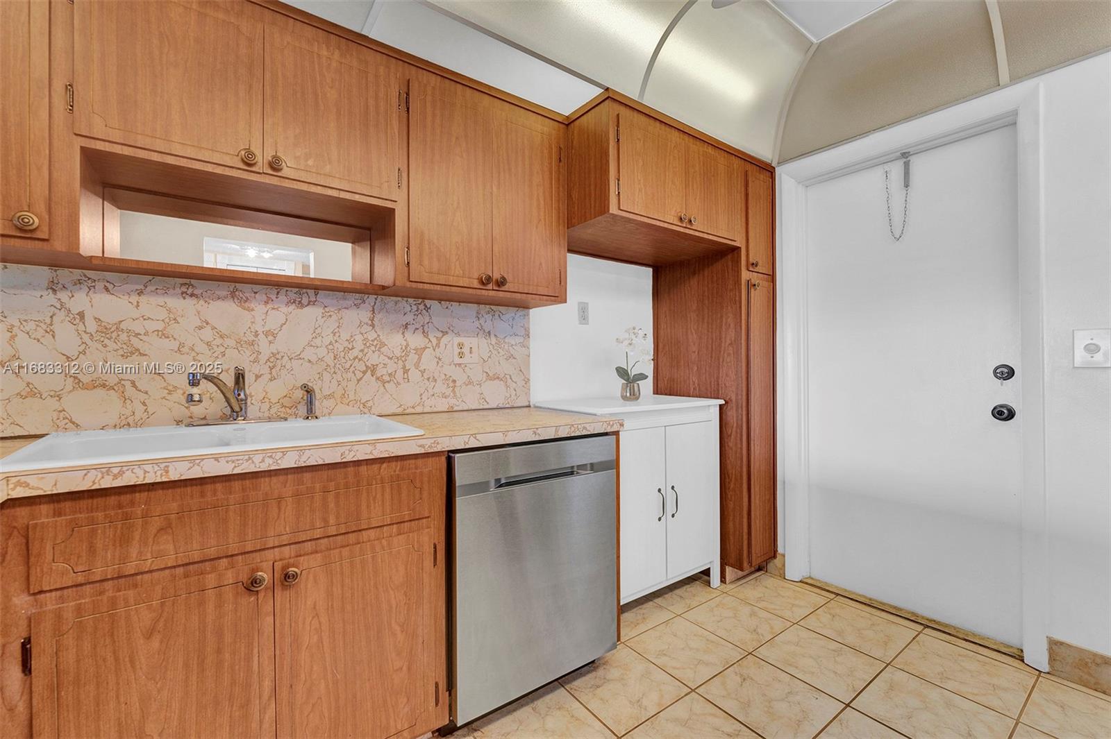 A kitchen features wood cabinets, a stainless steel dishwasher, a white sink, and tiled flooring — 330 SE 2nd St # 303F, Hallandale Beach FL 33009, HALLANDALE BEACH, FL
