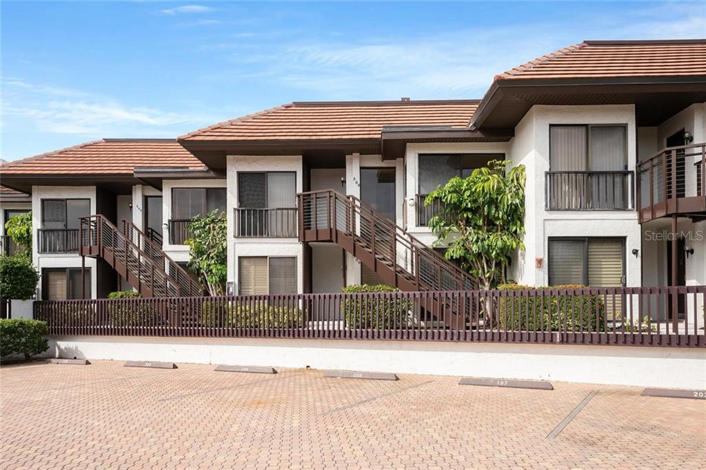 A two-story apartment building features brown staircases, balconies, and a paved parking lot in front — 5393 GULF OF MEXICO DRIVE UNIT 208, LONGBOAT KEY, FL