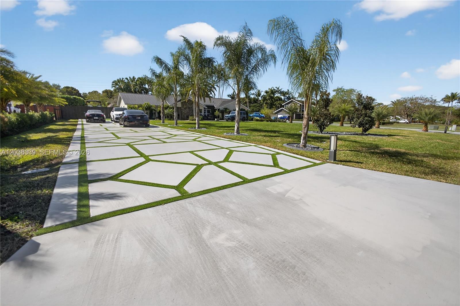 A long driveway features geometric concrete pavers with grass strips leading to a suburban house — 15050 SW 167th St, Miami FL 33187, MIAMI, FL
