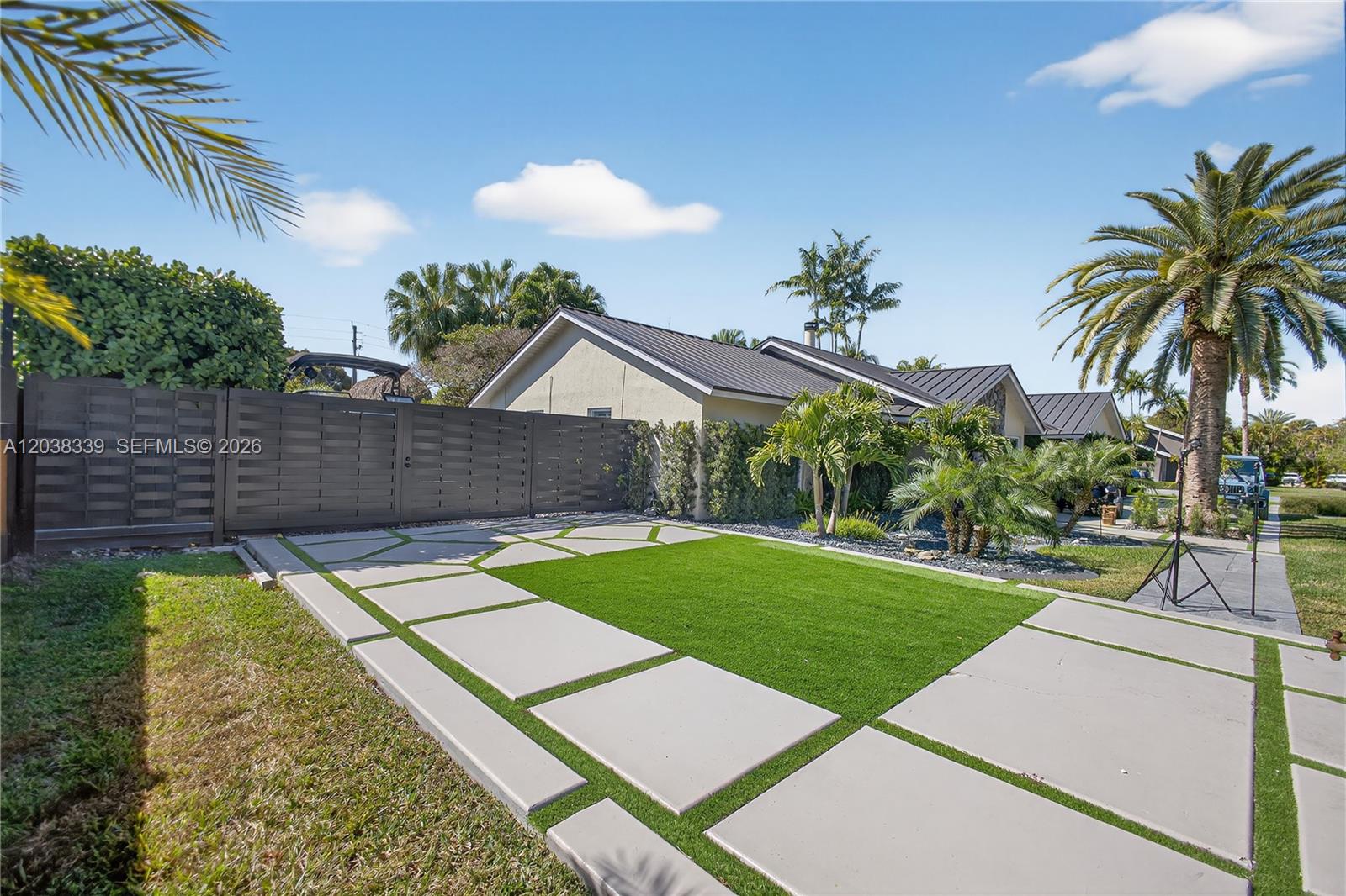 A modern driveway features large concrete pavers interspersed with patches of artificial green turf — 15050 SW 167th St, Miami FL 33187, MIAMI, FL