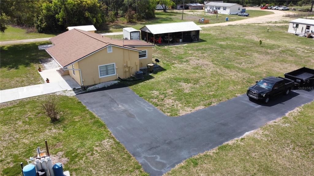 An aerial view shows a tan house with an asphalt driveway and a detached carport — 2305 STATE ROAD 33 HIGHWAY, CLERMONT, FL