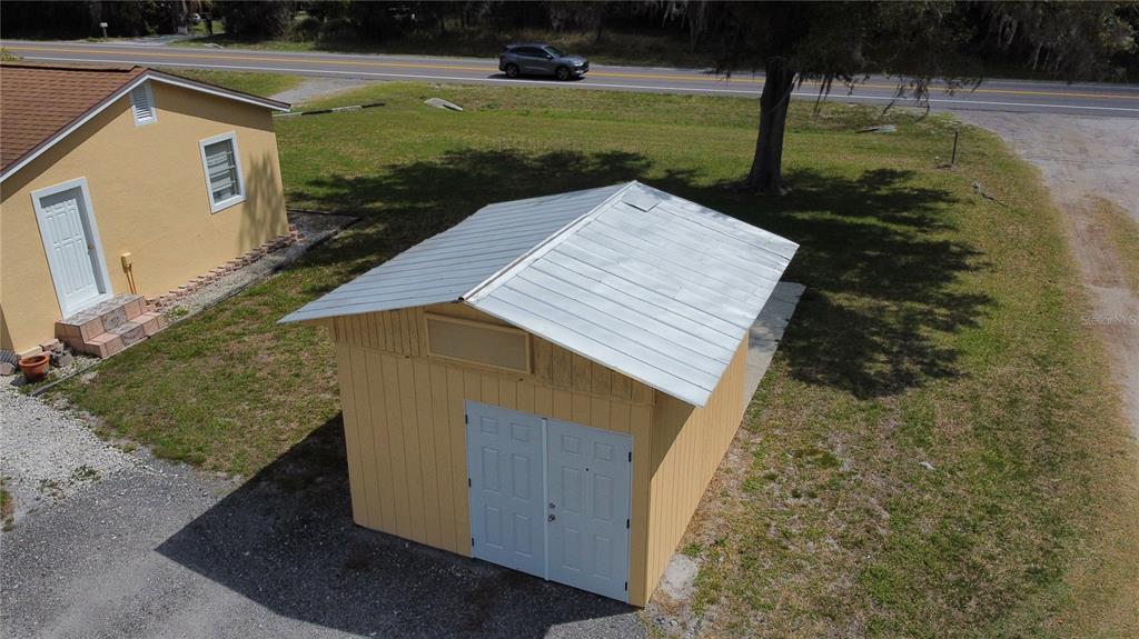 An aerial view shows a yellow shed with a metal roof next to a house — 2305 STATE ROAD 33 HIGHWAY, CLERMONT, FL