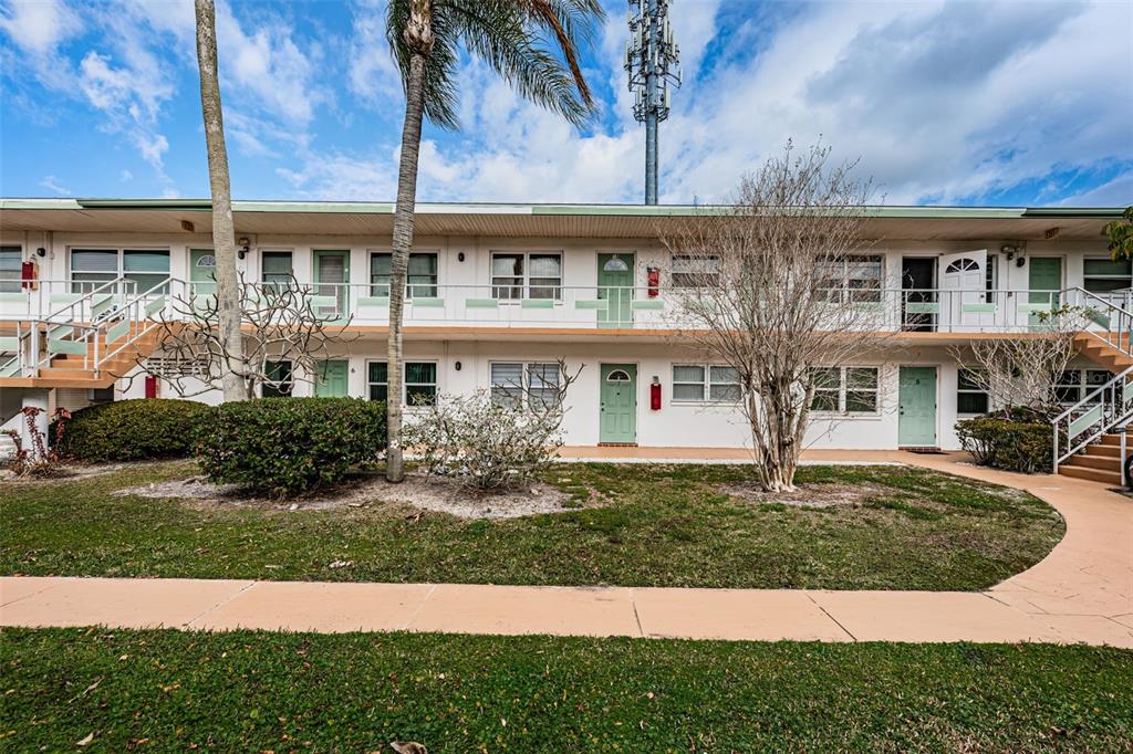 A two-story apartment building with a walkway, palm tree, and landscaping in front — 5955 18TH STREET N UNIT 7, ST PETERSBURG, FL