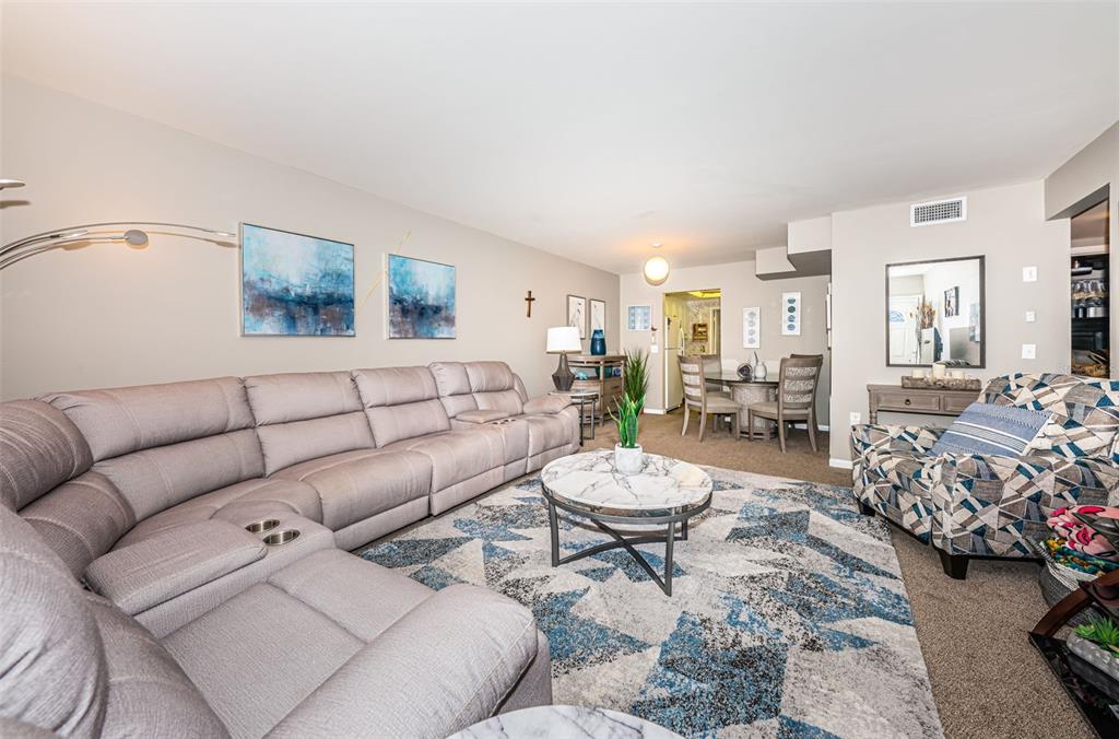 A living room features a large sectional sofa, a patterned armchair, and a marble coffee table — 5955 18TH STREET N UNIT 7, ST PETERSBURG, FL