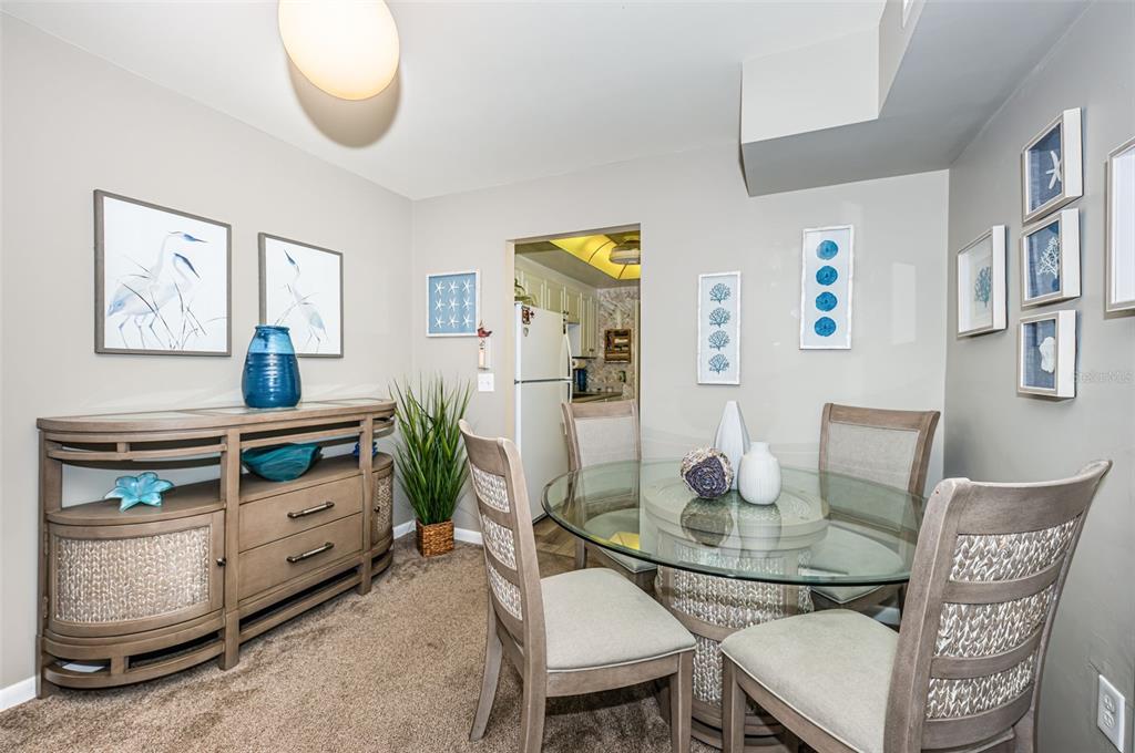 A dining area features a glass-topped table, four chairs, a wooden sideboard, and coastal decor — 5955 18TH STREET N UNIT 7, ST PETERSBURG, FL