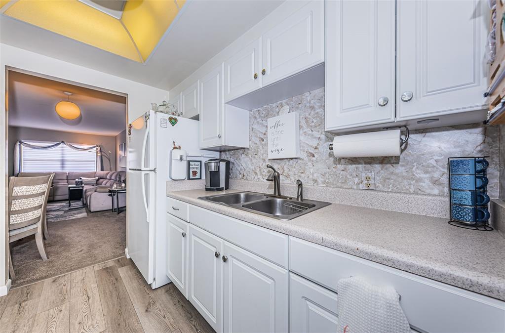 A kitchen features white cabinets, a double-basin sink, and a view into the living room — 5955 18TH STREET N UNIT 7, ST PETERSBURG, FL