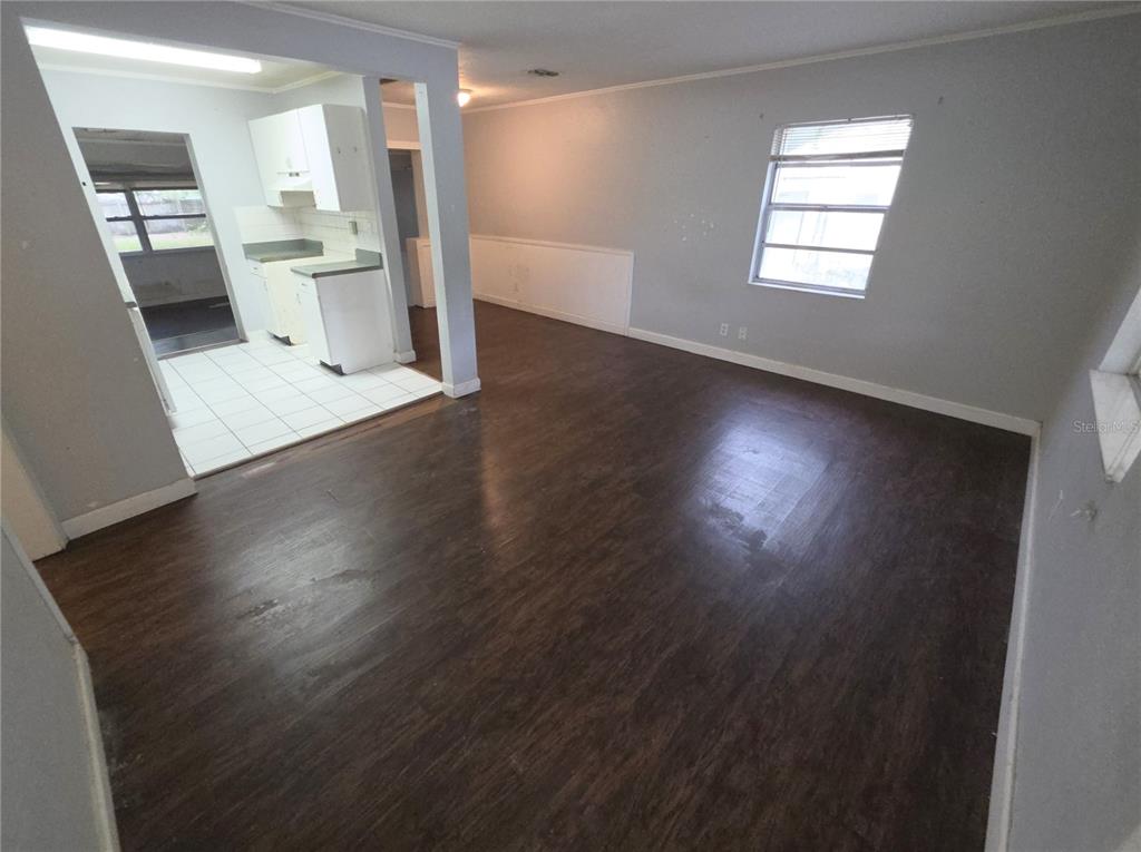 An interior view shows a living room with dark wood flooring leading to a tiled kitchen — 1222 ELDRIDGE STREET, CLEARWATER, FL
