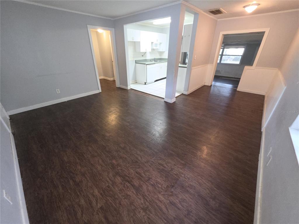 An open-concept living area features dark wood-look flooring, light gray walls, and a white kitchen — 1222 ELDRIDGE STREET, CLEARWATER, FL