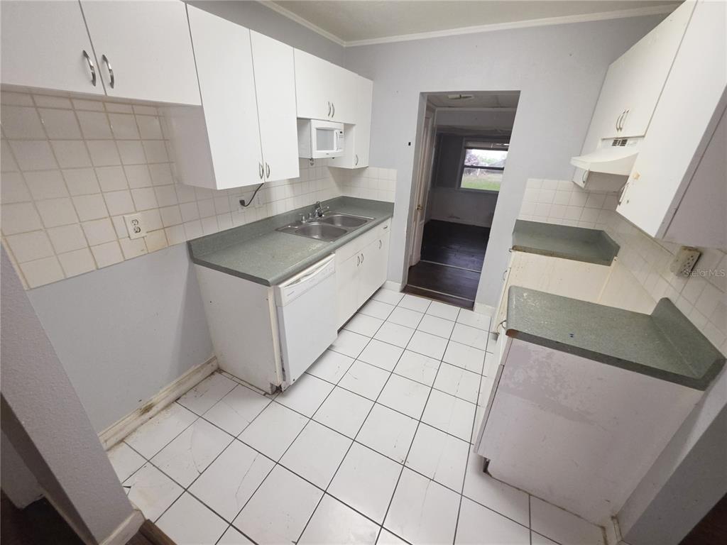 A kitchen with white cabinets, green countertops, white tiled floors, and a doorway to another room — 1222 ELDRIDGE STREET, CLEARWATER, FL