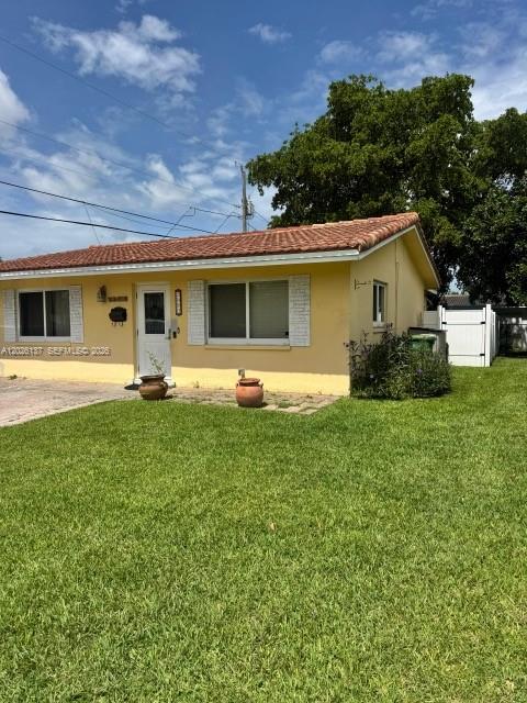 A yellow single-story house with a tiled roof sits behind a green lawn — 5403 NW 27th Ave, Tamarac FL 33309, TAMARAC, FL