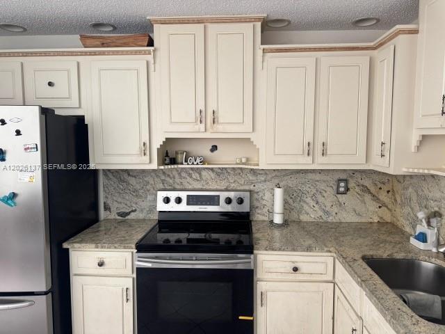 A kitchen features off-white cabinets, granite countertops, and a black stove and refrigerator — 5403 NW 27th Ave, Tamarac FL 33309, TAMARAC, FL