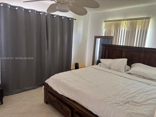 A bedroom features a large wooden bed, gray curtains, and a ceiling fan — 5403 NW 27th Ave, Tamarac FL 33309, TAMARAC, FL