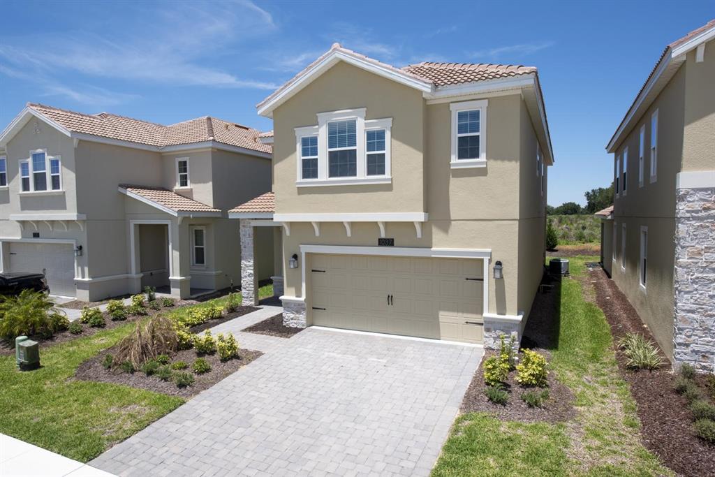 A two-story tan house with a paved driveway and a two-car garage — 1037 BLACKWOLF RUN ROAD, DAVENPORT, FL