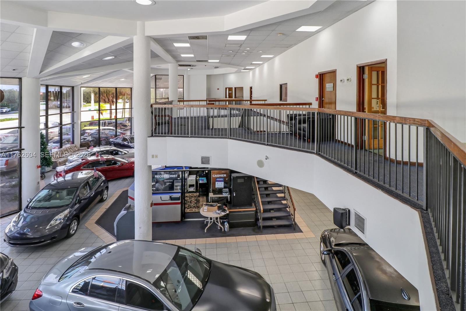 An indoor car dealership showroom features a mezzanine level, tiled floors, and multiple vehicles — 1450 N State Road 7, Hollywood FL 33021, HOLLYWOOD, FL