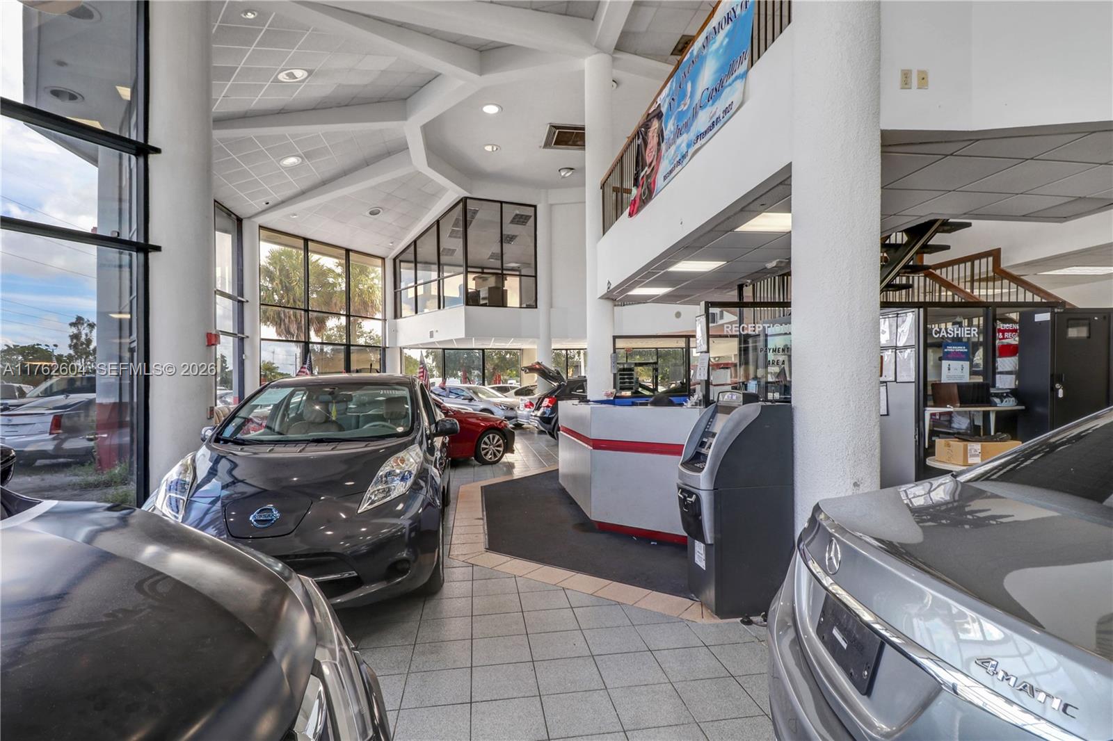 This car dealership showroom features tiled floors, a reception desk, and several parked vehicles — 1450 N State Road 7, Hollywood FL 33021, HOLLYWOOD, FL