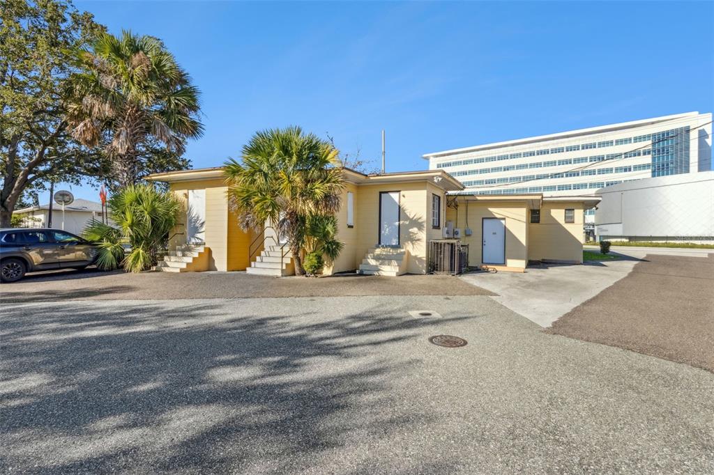 A yellow one-story commercial building with palm trees and a large office complex behind it — 1231 LAKELAND HILLS BOULEVARD, LAKELAND, FL