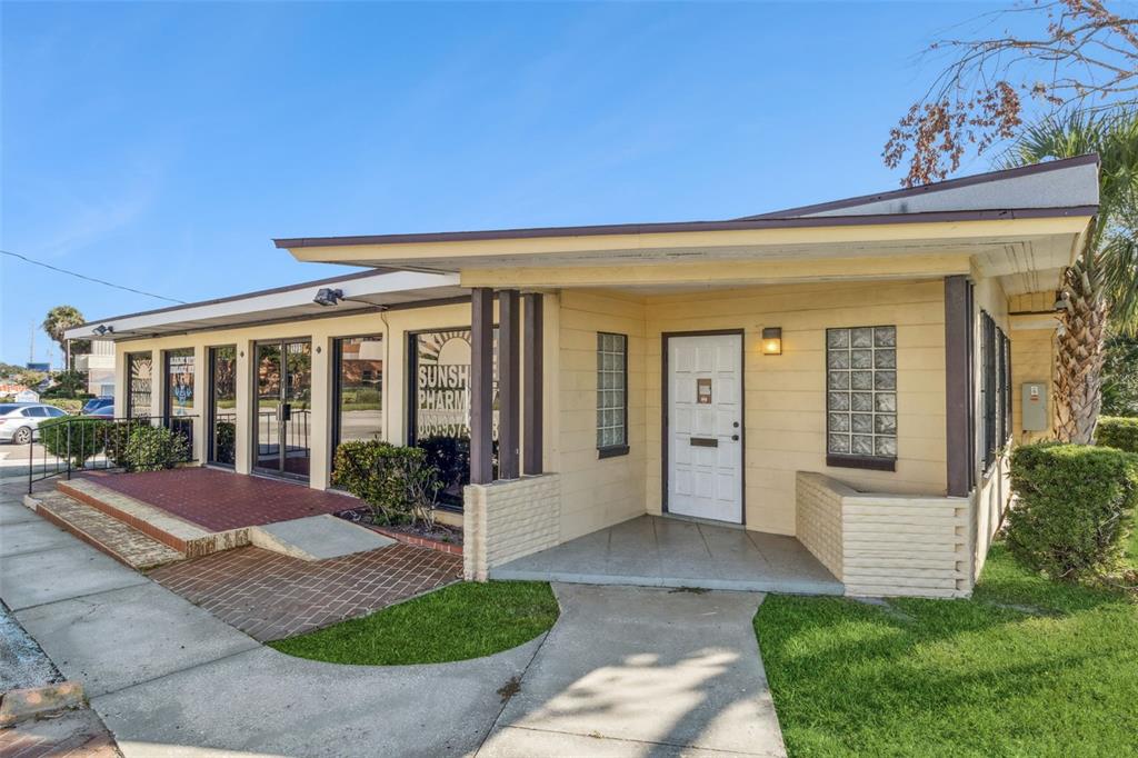 A single-story commercial building with a brick-paved entrance, glass storefront windows, and a covered porch — 1231 LAKELAND HILLS BOULEVARD, LAKELAND, FL