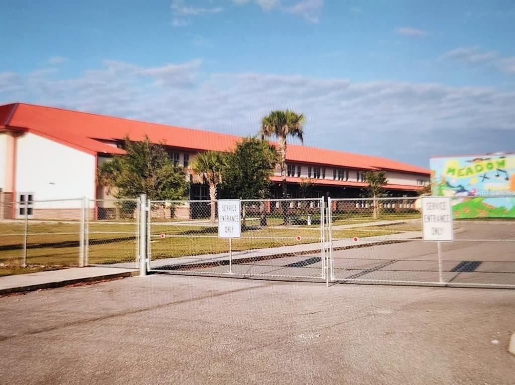 A chain-link gate blocks the entrance to a school building with a red roof — 267 CAPATOLA STREET, PORT CHARLOTTE, FL