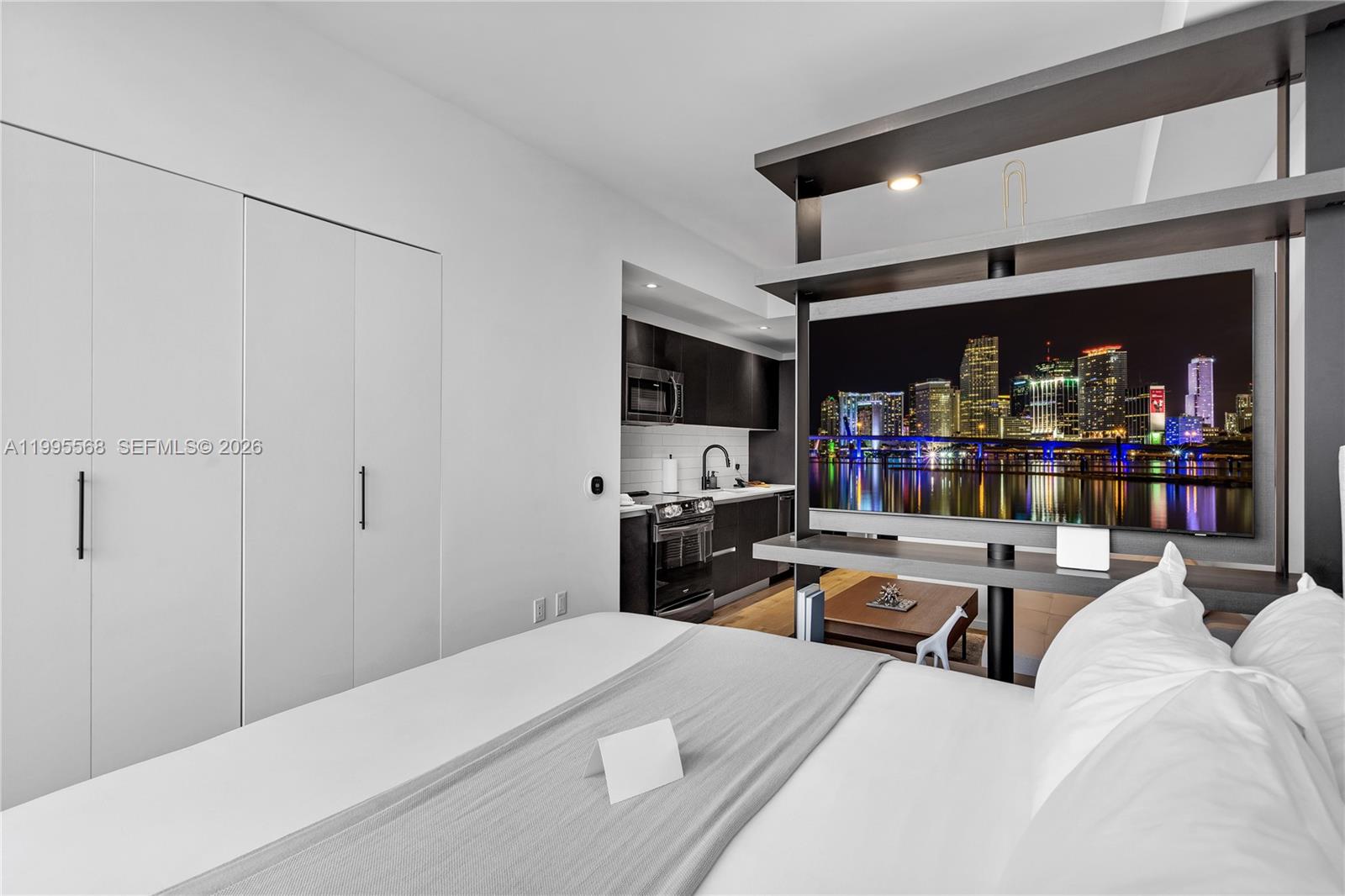 A modern studio apartment features a bed, a kitchen, and a central television partition — 398 NE 5th St # 4712, Miami FL 33132, MIAMI, FL