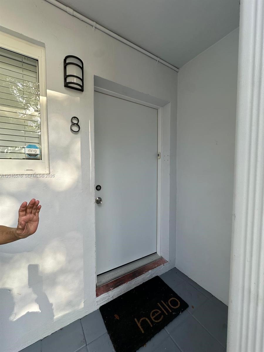 A white front door with the number eight is positioned next to a window — 6805 SW 88th St # 8, Pinecrest FL 33156, PINECREST, FL
