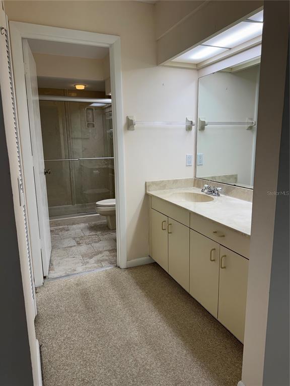 A bathroom with a vanity, mirror, and a separate room containing a shower and toilet — 4767 WINSLOW BEACON UNIT 25, SARASOTA, FL