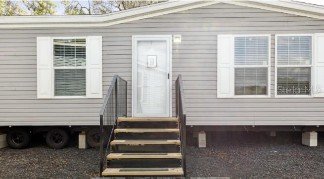 The exterior of a gray mobile home features a central door, stairs, and two windows — 27760 BERMONT ROAD, PUNTA GORDA, FL