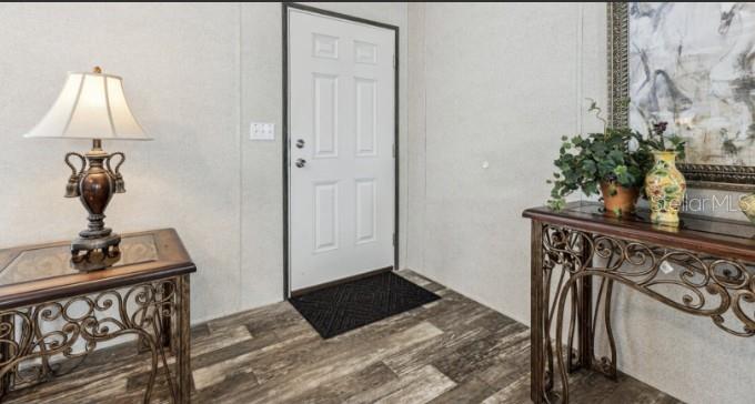 An entryway features a white door, wood-look flooring, and two ornate metal console tables — 27760 BERMONT ROAD, PUNTA GORDA, FL