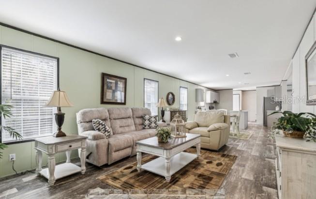 A living room with light green walls, wood-look flooring, a sofa, armchair, and coffee table — 27760 BERMONT ROAD, PUNTA GORDA, FL