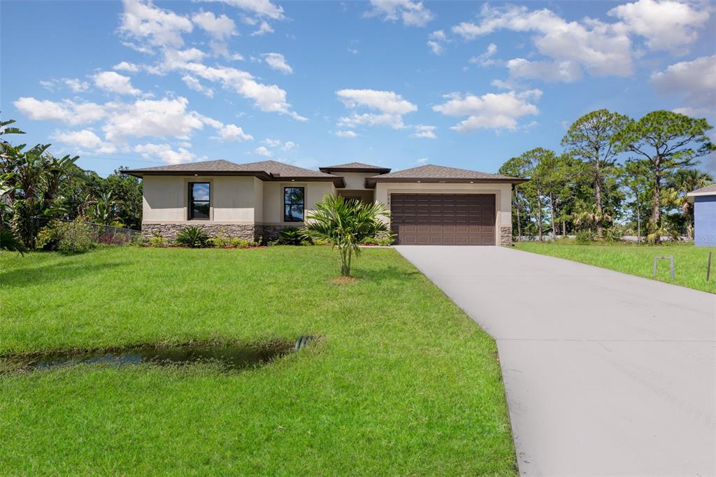 A single-story house with a beige exterior, stone accents, and a two-car garage — 1319 SCHNEIDER STREET SW, PALM BAY, FL